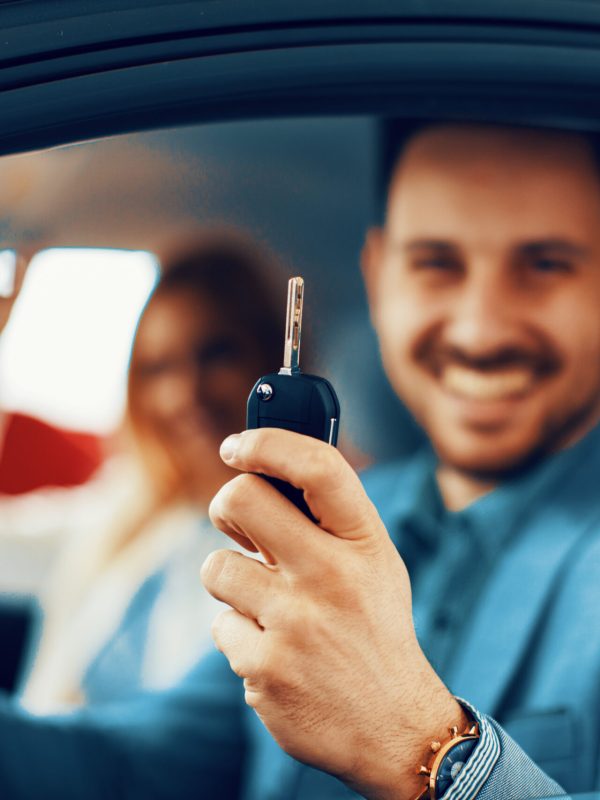 Young couple holding the keys of a new car. Selective focus on keys